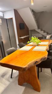 - une table en bois dans une pièce avec des chaises et un escalier dans l'établissement Pôr do sol house, à Aracaju