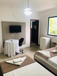 a room with two beds and a table and a tv at Quinta Da Bica D'Agua Village in Florianópolis +65 photos