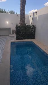 una piscina azul con una palmera junto a un edificio en Casa Sererno I, en Cuatrociénegas de Carranza