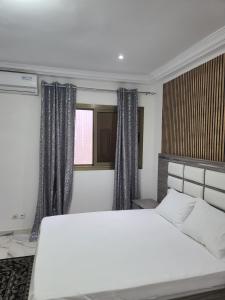 a bedroom with a large white bed and a window at Zeynab appt mamelles in Dakar