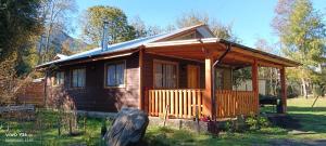 a cabin in the woods with a porch at Cabaña Entre Rosas in Coñaripe