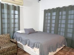 Un dormitorio con una cama y una silla y ventanas. en Lapacho Roga, en Asunción