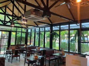 a dining room with tables and chairs and windows at มิสเตอร์เน็กซ์รีสอร์ท อยุธยา in Sathani Ayutthaya