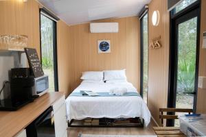 a bedroom with a bed and a tv and window at Rocky Creek Escape by Tiny Away in Kanighan