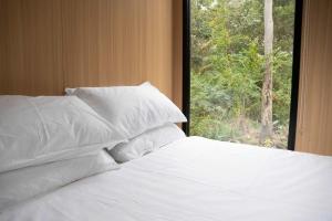 a bed with white pillows in front of a window at Rocky Creek Escape by Tiny Away in Kanighan