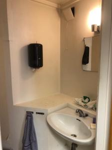 a bathroom with a sink and a tv on the wall at Billigst i Arendal sentrum uten dusj næringslokaler klinikk og verksted in Arendal