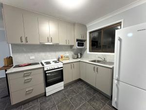a kitchen with white cabinets and a white refrigerator at Nestled on Smith in Stanthorpe