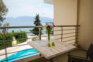 a table with a vase of flowers and fruit on a balcony at Deluxe Kefalonia Apartment Apartment Leyland 1 Bedroom Pool And Sea View Karavomilos in Karavomylos