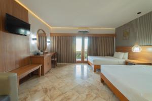 a hotel room with two beds and a television at Nirmala Hotel Jimbaran in Jimbaran