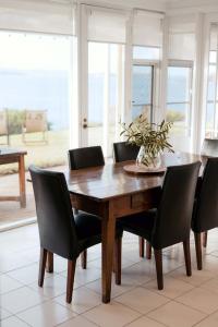 Encounter BayWhalers Rest Ocean front Whale watching的一张餐桌,配有黑色椅子和花瓶
