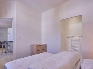 a white bedroom with a bed and a mirror at Appartement 2 pers avec Parking et Wifi à Barbotan - FR-1-841-13 in Barbotan-les-Thermes