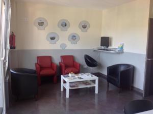 una sala de espera con sillas rojas y una mesa en Albergue As Eiras, en Lires