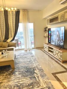 a living room with a television and a couch at Mivida Emaar New Cairo For Rent in New cairo