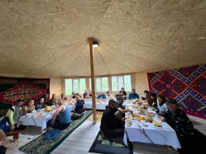 a group of people sitting at tables in a room at Taasir Yurt Camp in Dzhangyaryk
