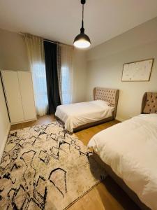 a bedroom with two beds and a rug on the floor at Mivida Emaar New Cairo For Rent in New cairo