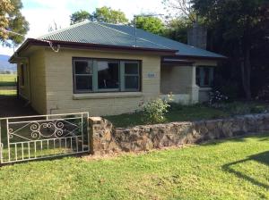 Rubicon Views Cottage في Acheron: منزل صغير أمامه سور حجري