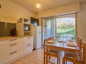 a kitchen with a table with chairs and a refrigerator at Charmant T1 bis avec jardin privatif à Barbotan-les-Thermes - FR-1-841-64 in Barbotan-les-Thermes