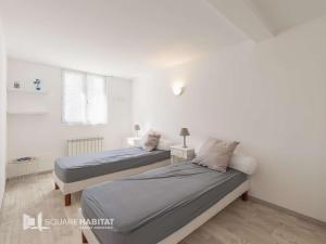 two beds in a room with white walls at Appartement T3 4 pers. avec Terrasse, Wifi, Parking, Animaux admis - FR-1-841-58 in Barbotan-les-Thermes