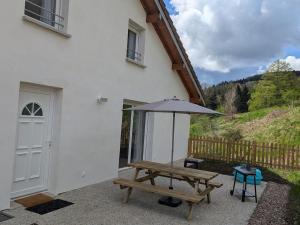 - une table de pique-nique et un parasol à côté d'une maison dans l'établissement Gîte familial à La Croix-aux-Mines avec entrée privative - FR-1-589-826, à La Croix-aux-Mines