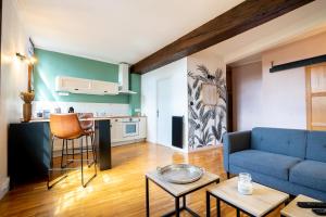 a living room with a blue couch and a kitchen at T3 Classé Monument Historique XVIe Saumur Centre in Saumur