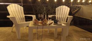 two white chairs and a table with two glasses of wine at MeNTA GLAMPING in Sasaima +19 photos