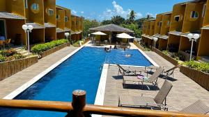 a pool at a hotel with chairs and people in it at Casa Imbassai in Imbassai