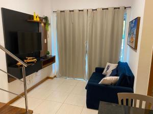 a living room with a blue couch and a flat screen tv at Casa Imbassai in Imbassai +14 photos