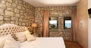 a bedroom with a stone wall with a bed and windows at Executive Rhodes Villa Villa Althea 2 Bedroom Villa With Sea Views Pefkos in Pefki Rhodes