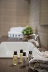a bathroom sink with four bottles of soap on a counter at Deluxe Kefalonia Apartment Apartment Canella 1 Bedroom Outdoor Pool Karavomilos in Karavomylos