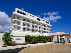 a large white building with palm trees in front of it at Lit Hotel NAKIJIN in Nakijin