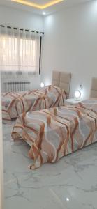 モナスティルにあるAppartement neuf luxueuxのベッドルーム1室(ベッド2台、オレンジと白の毛布付)