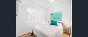a white bedroom with a bed and a window at Beachfront Getaway in Sydney