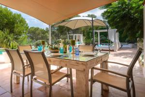 ein Tisch mit Stühlen und einem Sonnenschirm auf einer Terrasse in der Unterkunft Delightful Ibiza Villa Spectacular Mountain Views Villa Jasmine in Sant Rafael de Sa Creu