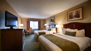a hotel room with two beds and a flat screen tv at Best Western Shepherdsville-Louisville South Hotel in Shepherdsville