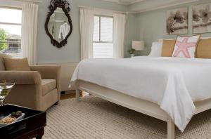 a bedroom with a large white bed and a chair at Shelter Island House in Shelter Island Heights +39 photos