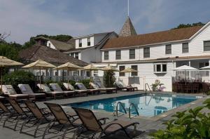 a swimming pool with lounge chairs and a building at Shelter Island House in Shelter Island Heights