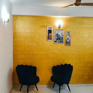 2 sillas en una habitación con una pared amarilla en Madhav Mohini Kunj -2 BHK Near Prem Mandir, en Vrindāvan