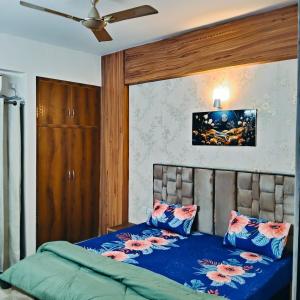 1 dormitorio con 1 cama con sábanas azules y ventilador en Madhav Mohini Kunj -2 BHK Near Prem Mandir, en Vrindāvan