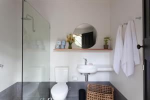 a bathroom with a toilet and a sink and a mirror at Garden Beds Glamping in Blackwood