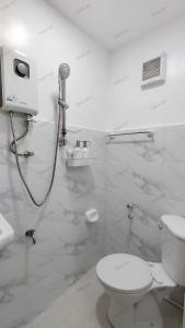 a white bathroom with a toilet and a shower at Tokai's Transient House in Legazpi