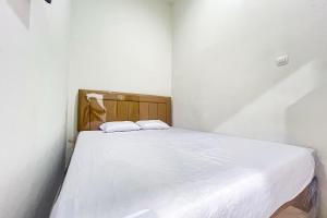 a small white room with a bed with two pillows at Guest House 21 RedPartner in Jakarta