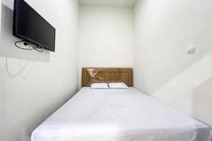 a small bedroom with a bed with a flat screen tv at Guest House 21 RedPartner in Jakarta