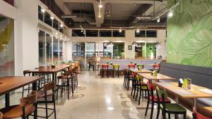 a restaurant with wooden tables and chairs and a green wall at Zuri Express Lippo Cikarang in Cikarang