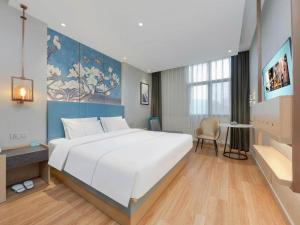 a bedroom with a large white bed and a desk at Magnotel Hotel Xiamen North Station Binhai in Xiamen