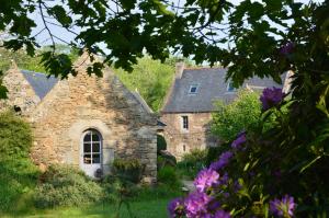 une maison en pierre dans un jardin avec des fleurs violettes dans l'établissement La Grange de Coatélan, à Plougonven