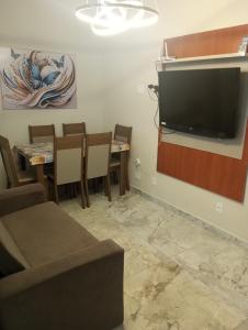 a living room with a tv and a table and chairs at Kitnet pé na areia in Praia Grande