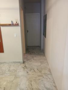 a hallway with a white wall and a tile floor at Kitnet pé na areia in Praia Grande