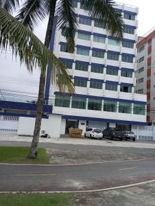 a palm tree in front of a large building at Kitnet pé na areia in Praia Grande