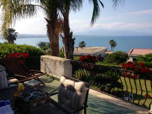 balkon z krzesłami i widokiem na ocean w obiekcie Villa Baia del Riccio w mieście Agnone Bagni