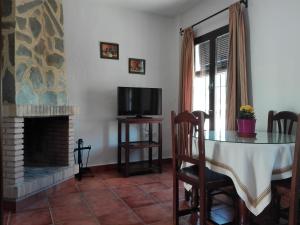 sala de estar con mesa, TV y chimenea en Casa Dominga, en El Bosque